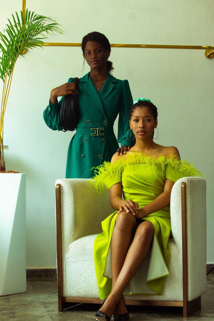 Two stylish women posing elegantly in vibrant dresses indoors.