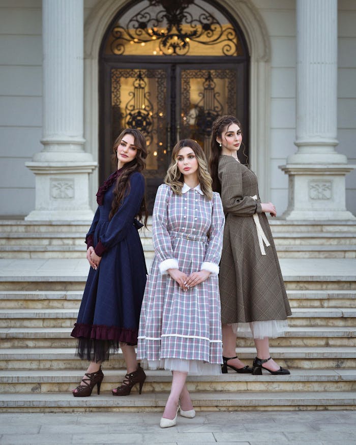 about-us-02 Three women in vintage dresses pose gracefully on manor steps. Beautiful and elegant fashion portrait.